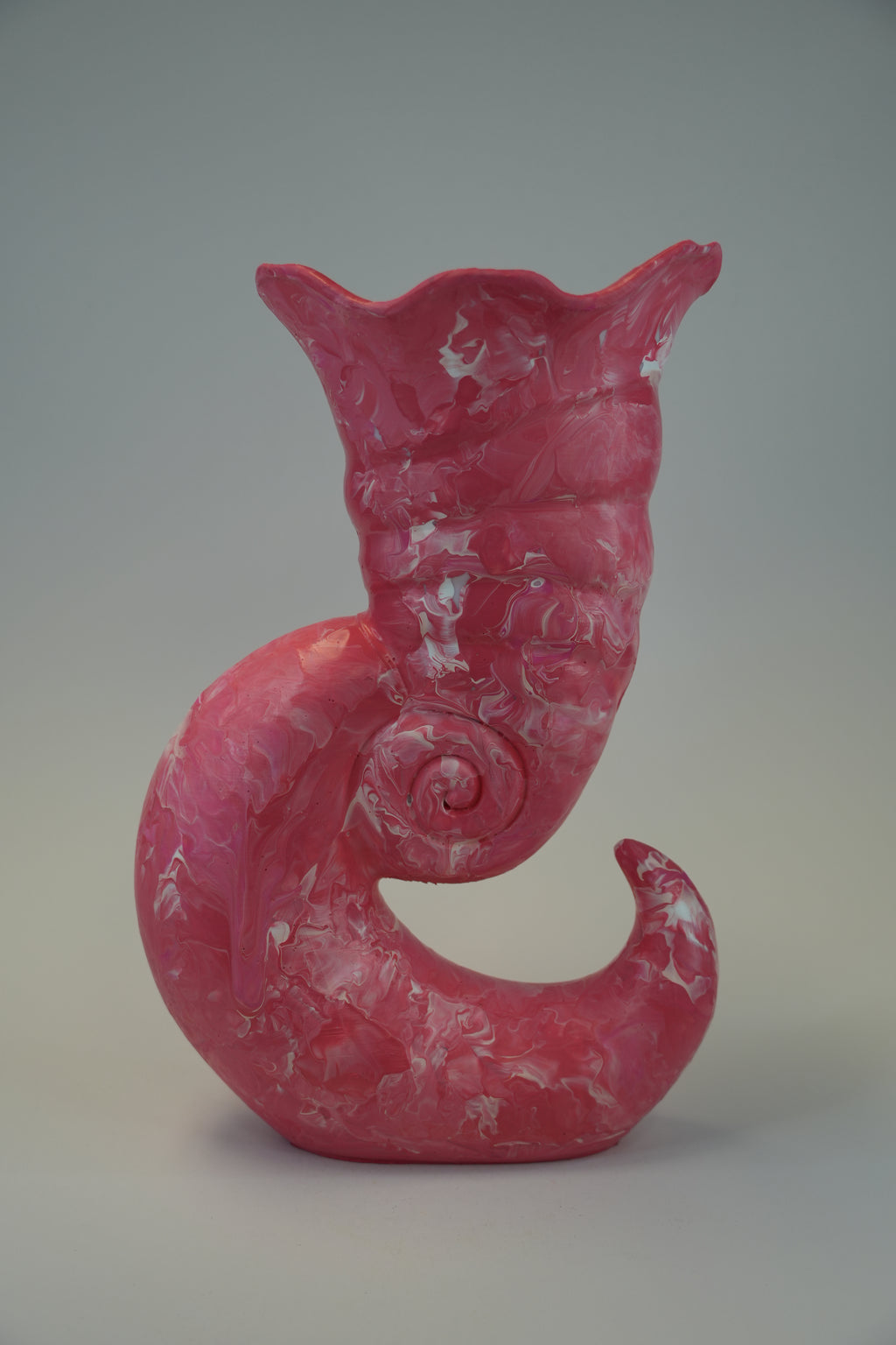 A sculptural pink ceramic vase with a coiled, serpent-like form and textured marbled surface, photographed against a neutral gray studio background.