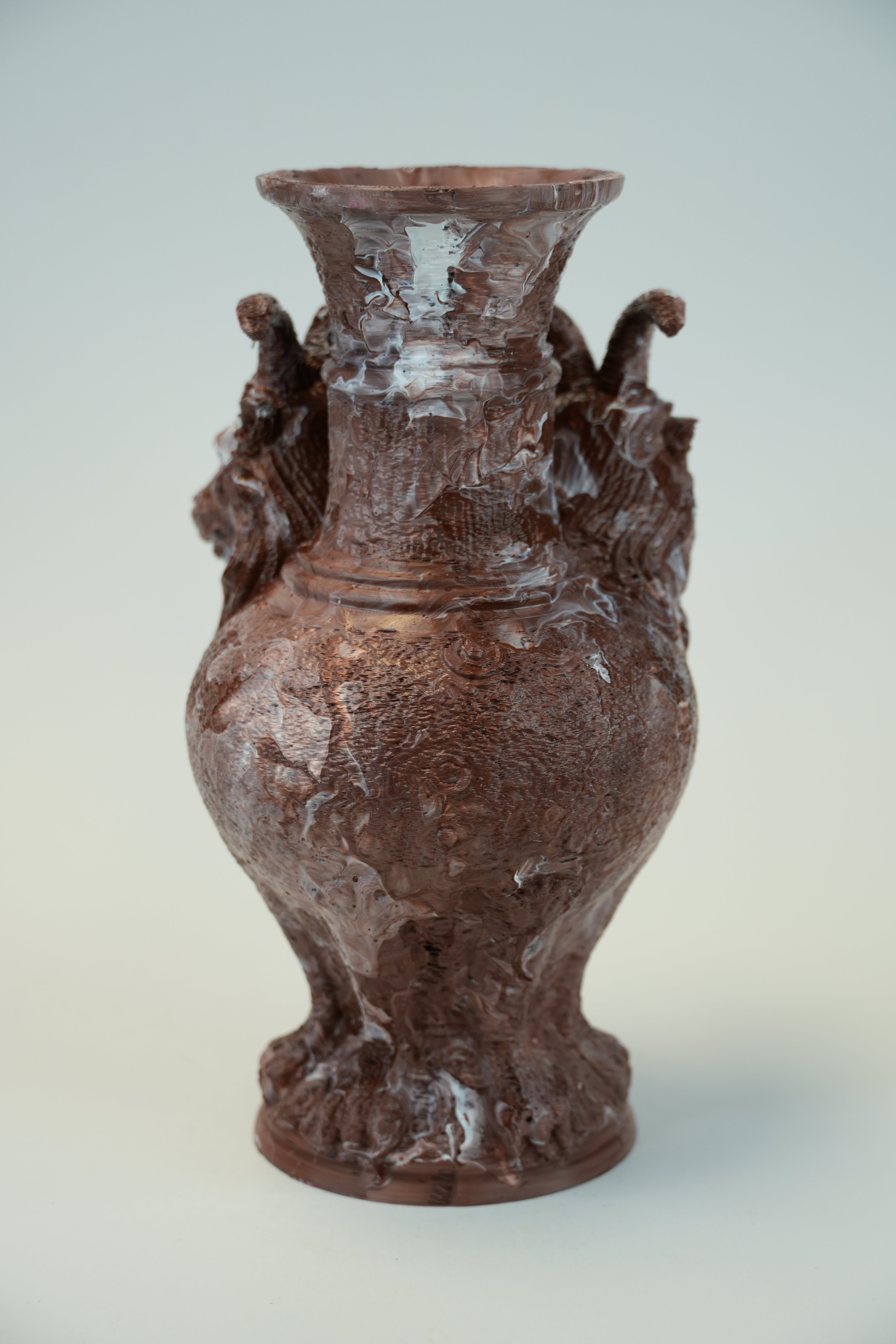 A brown ceramic vase with a textured, hand-painted dragon design and two dragon handles on the sides, set against a light gray background.