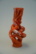 An abstract sculptural ceramic vase with a twisted, organic form in glossy terracotta orange and white marbled glaze, set against a neutral light gray background.