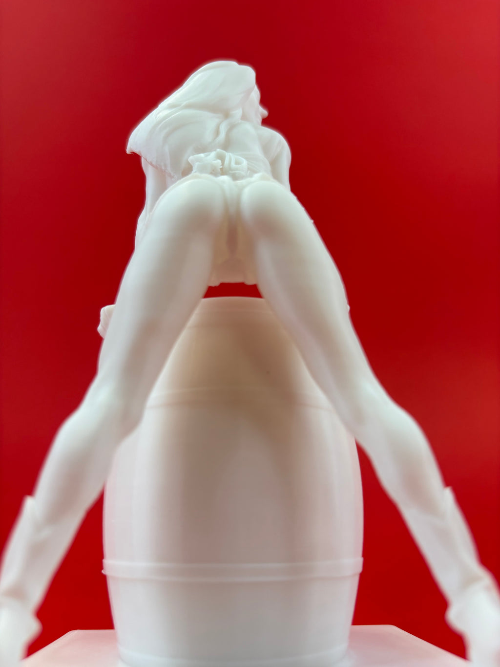 White sculpture of a figure against a red background