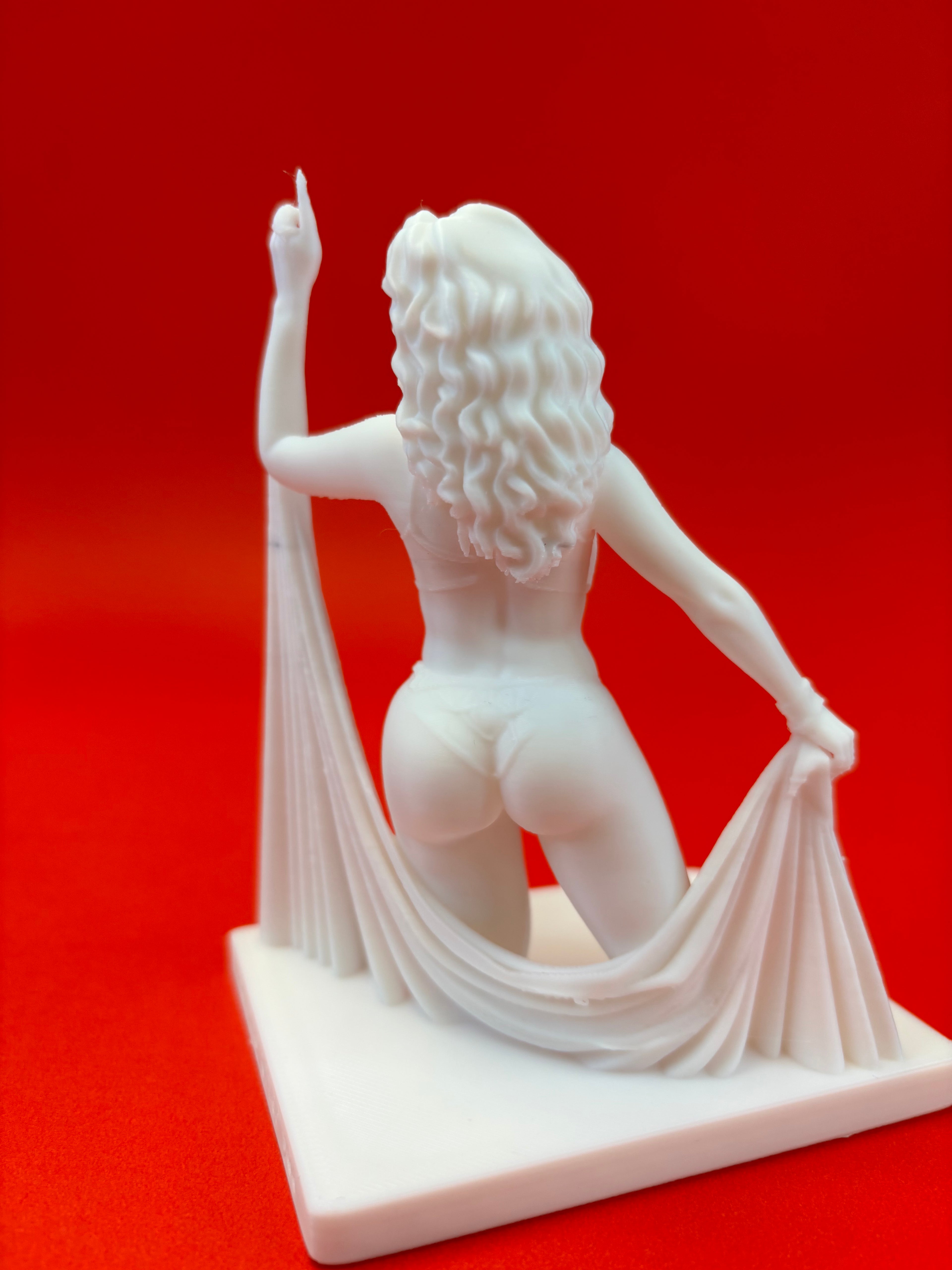 White statue of a figure with flowing fabric on a red background