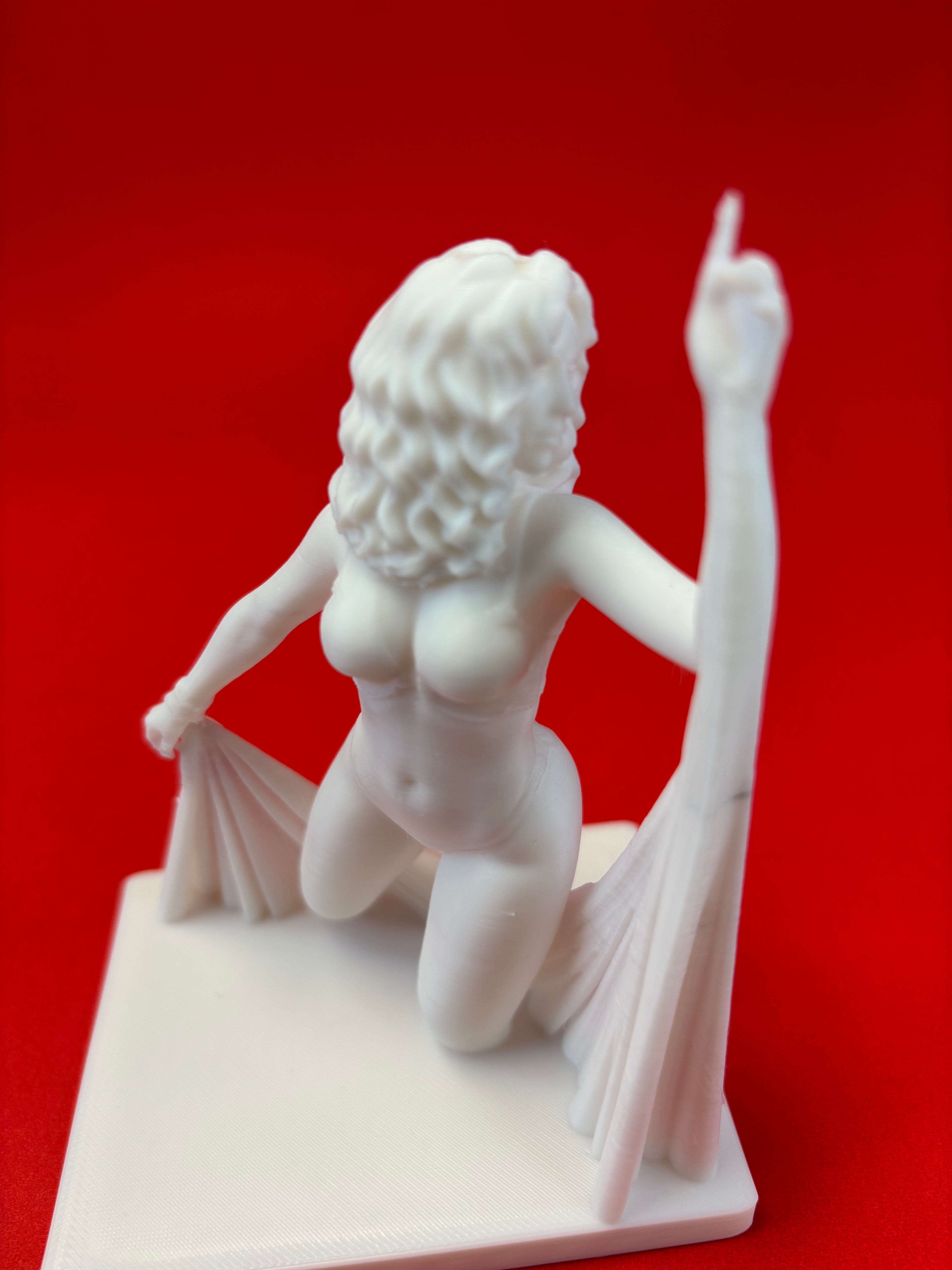 White sculpture of a draped figure on a red background