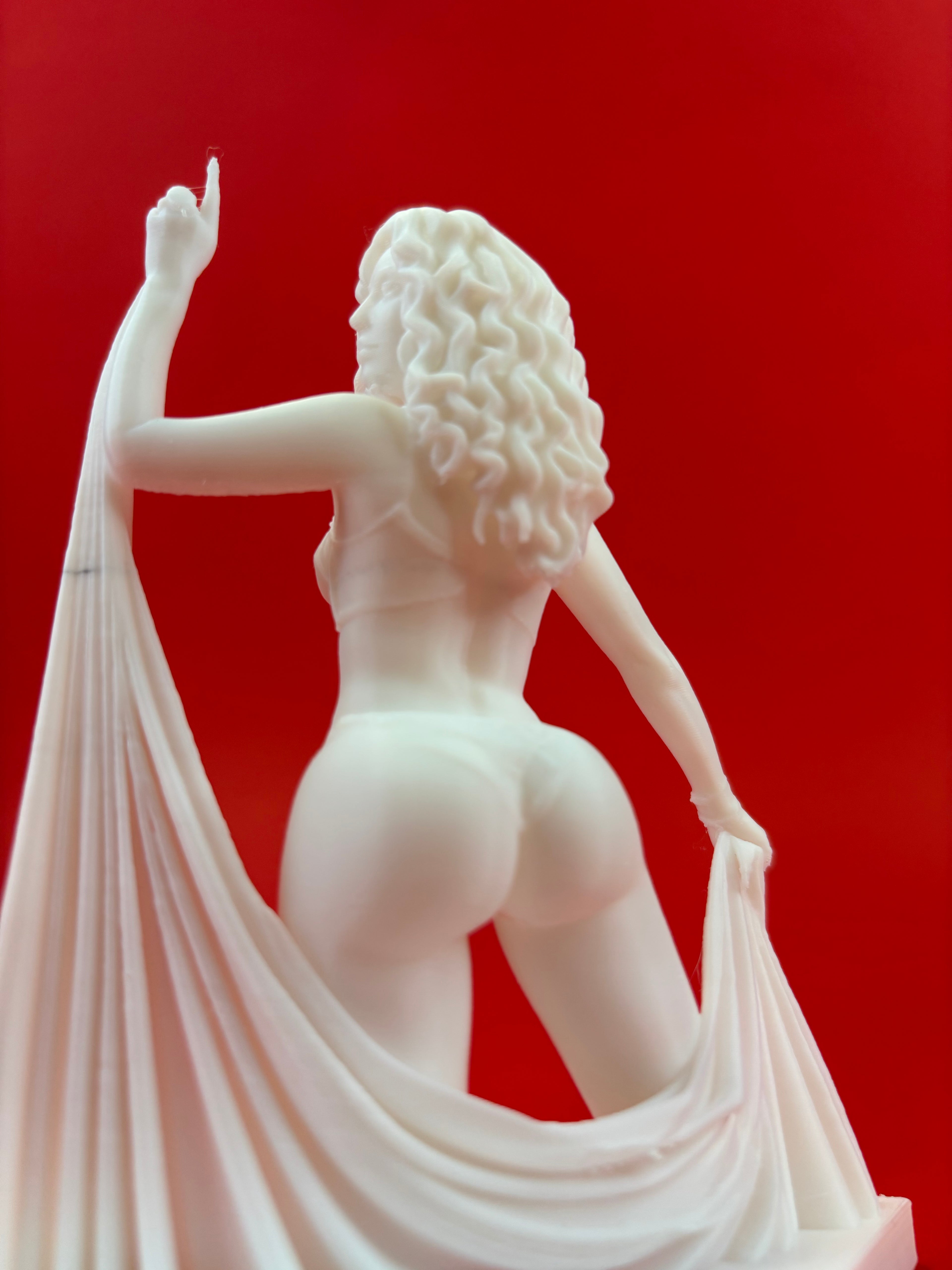 White sculpture of a woman with flowing hair on a red background