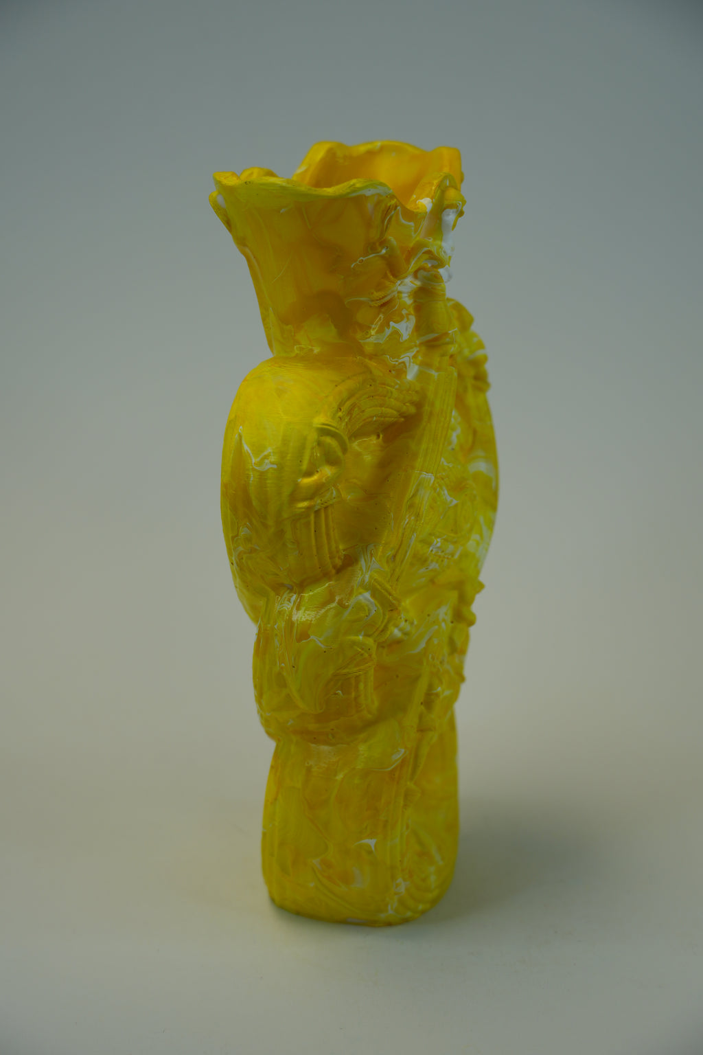 A bright yellow sculptural ceramic vase with a textured, hand-painted finish, standing on a neutral light gray background.