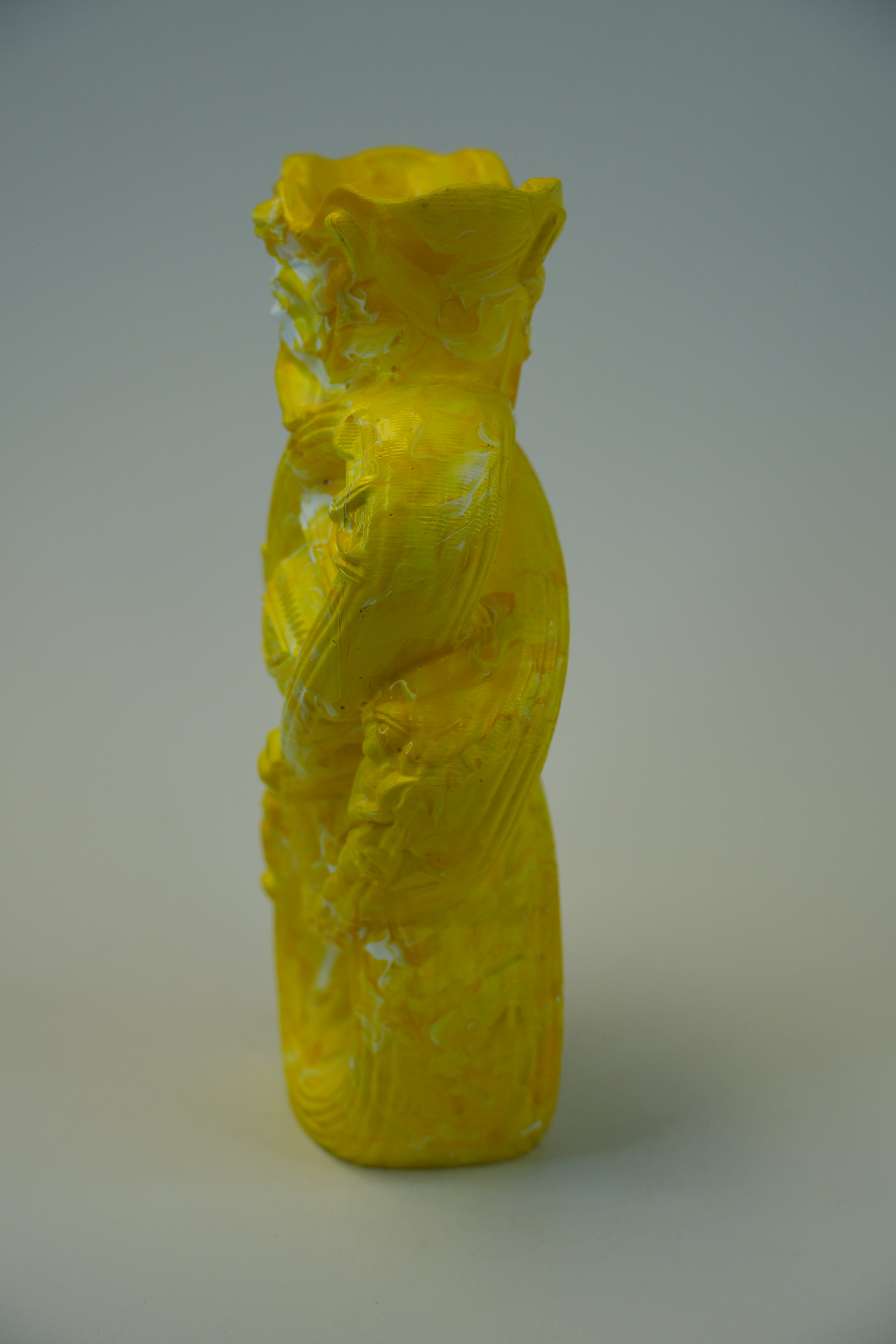 A bright yellow abstract sculptural wall-mounted object with textured, crumpled forms, photographed against a plain light gray wall.