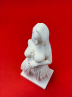 White sculpture of a nude figure on a red background