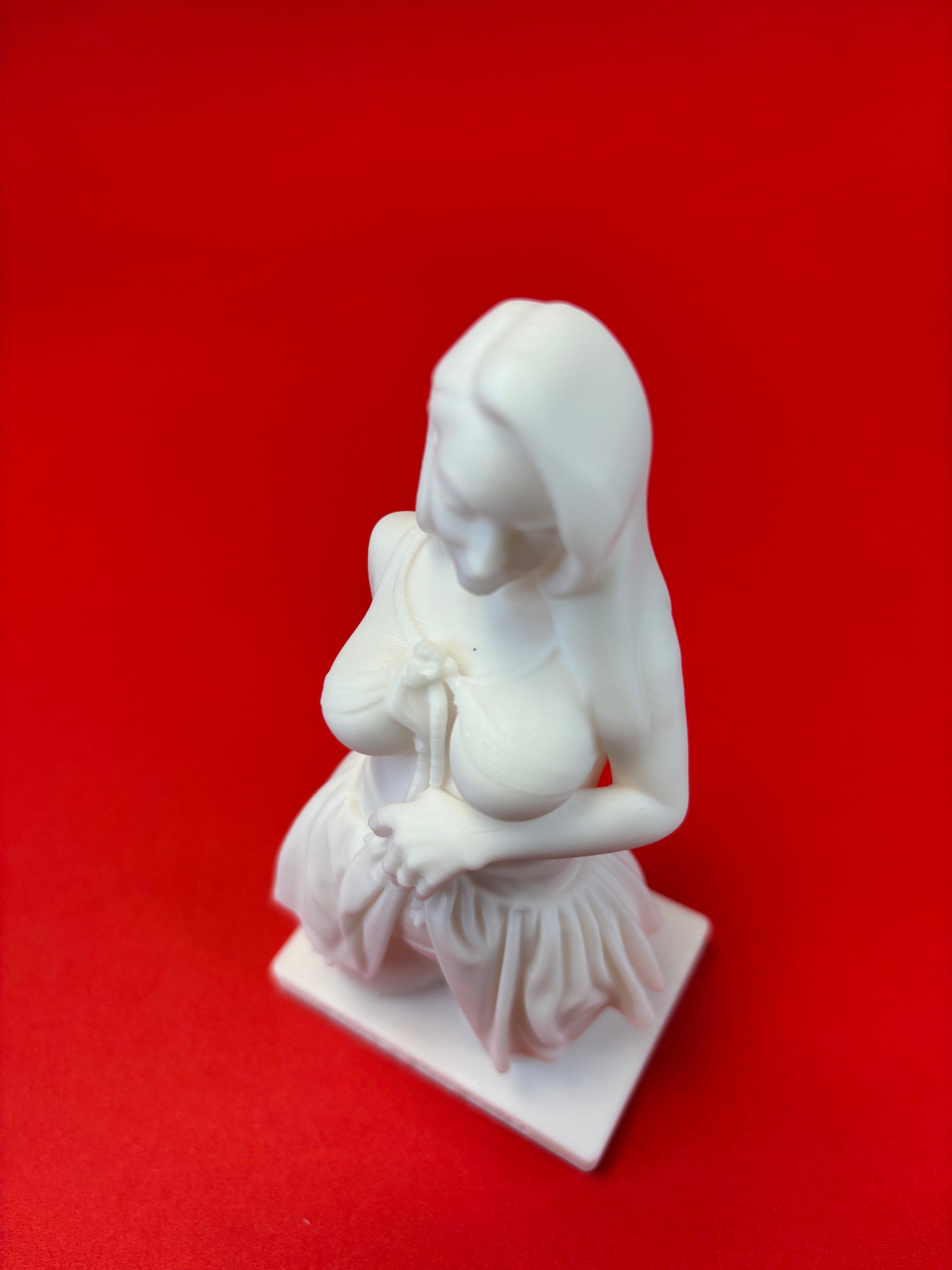 White sculpture of a nude figure on a red background
