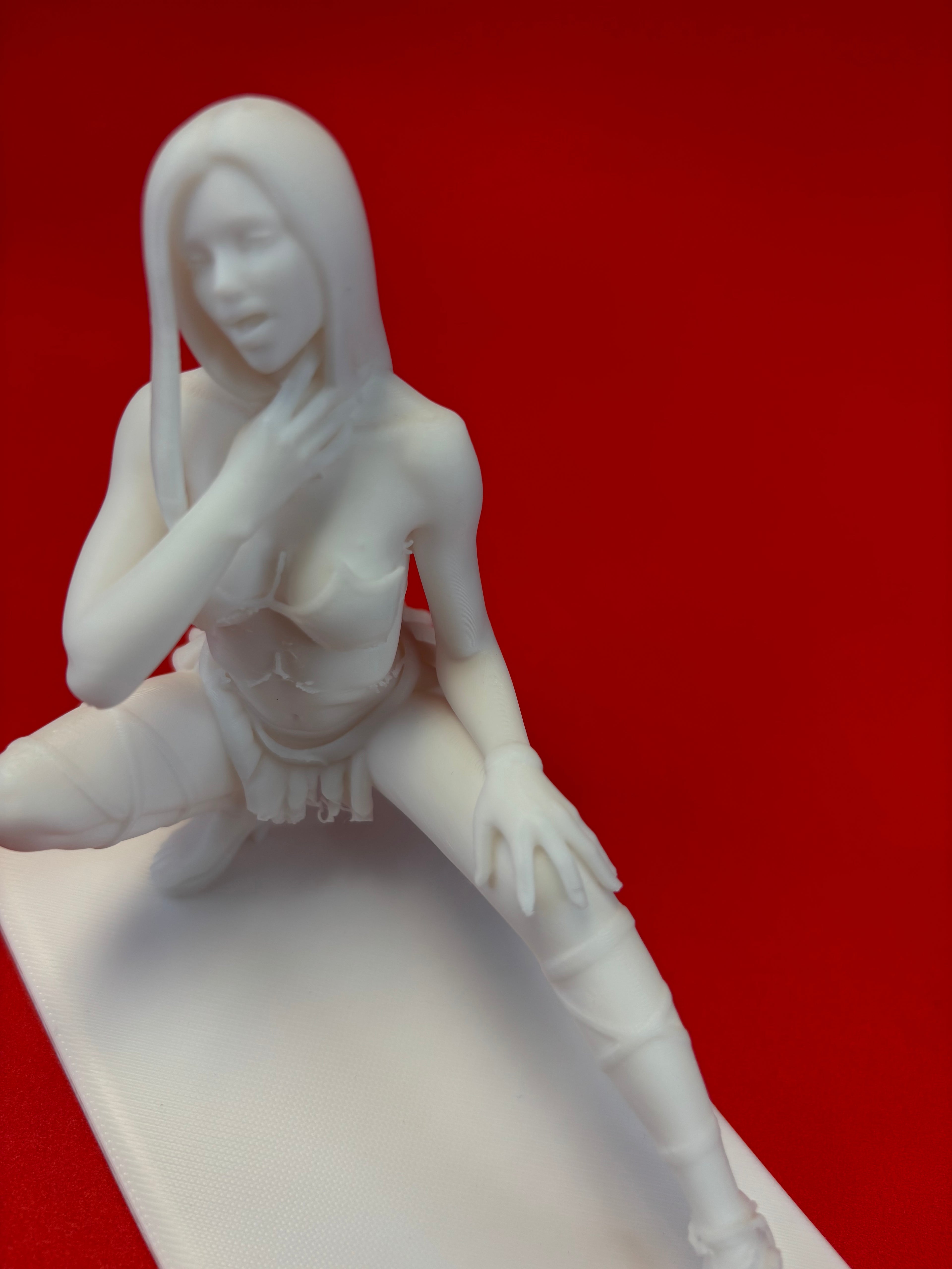 White figurine of a woman in a dynamic pose on a red background