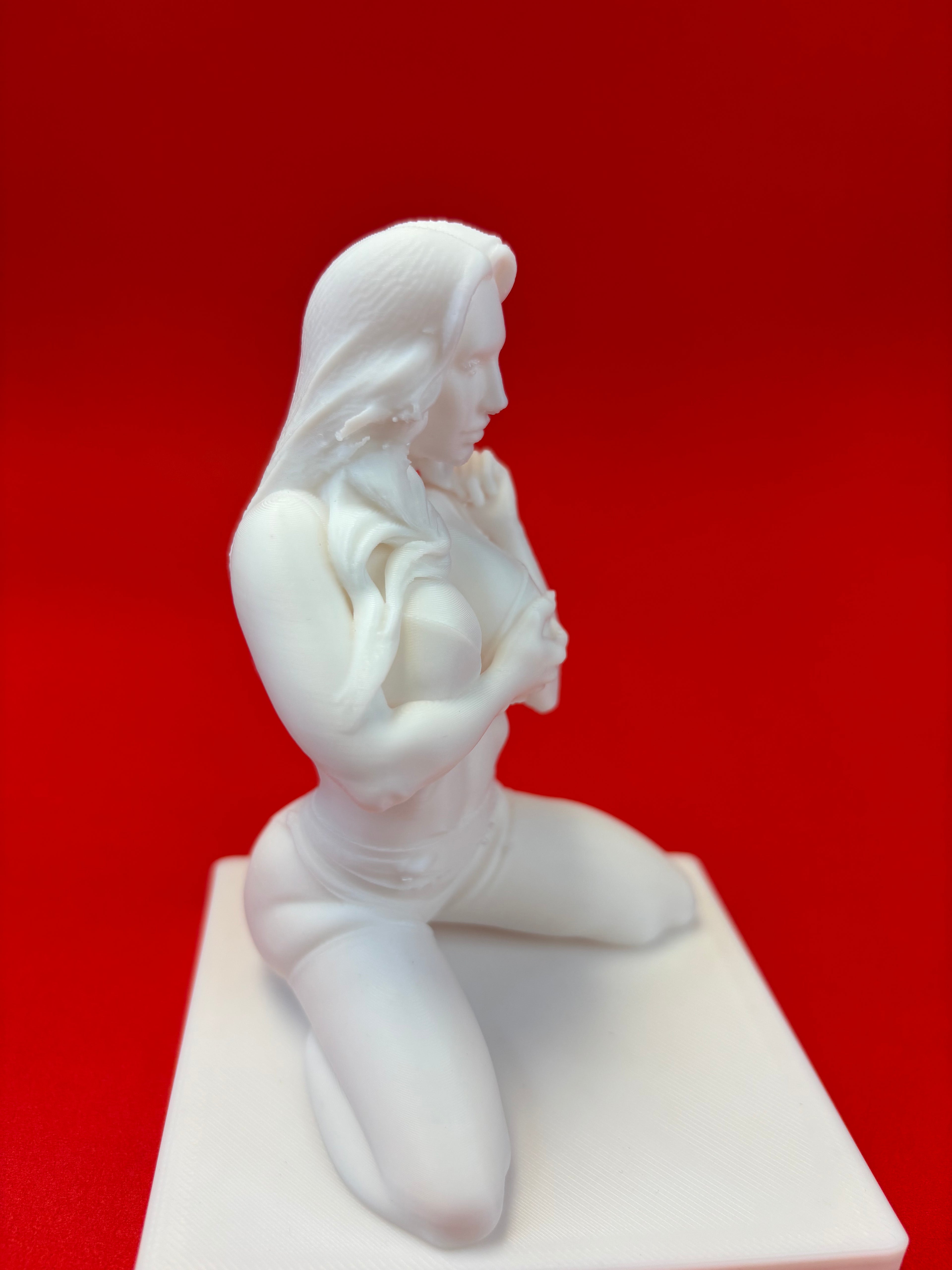 White sculpture of a reclining figure on a red background